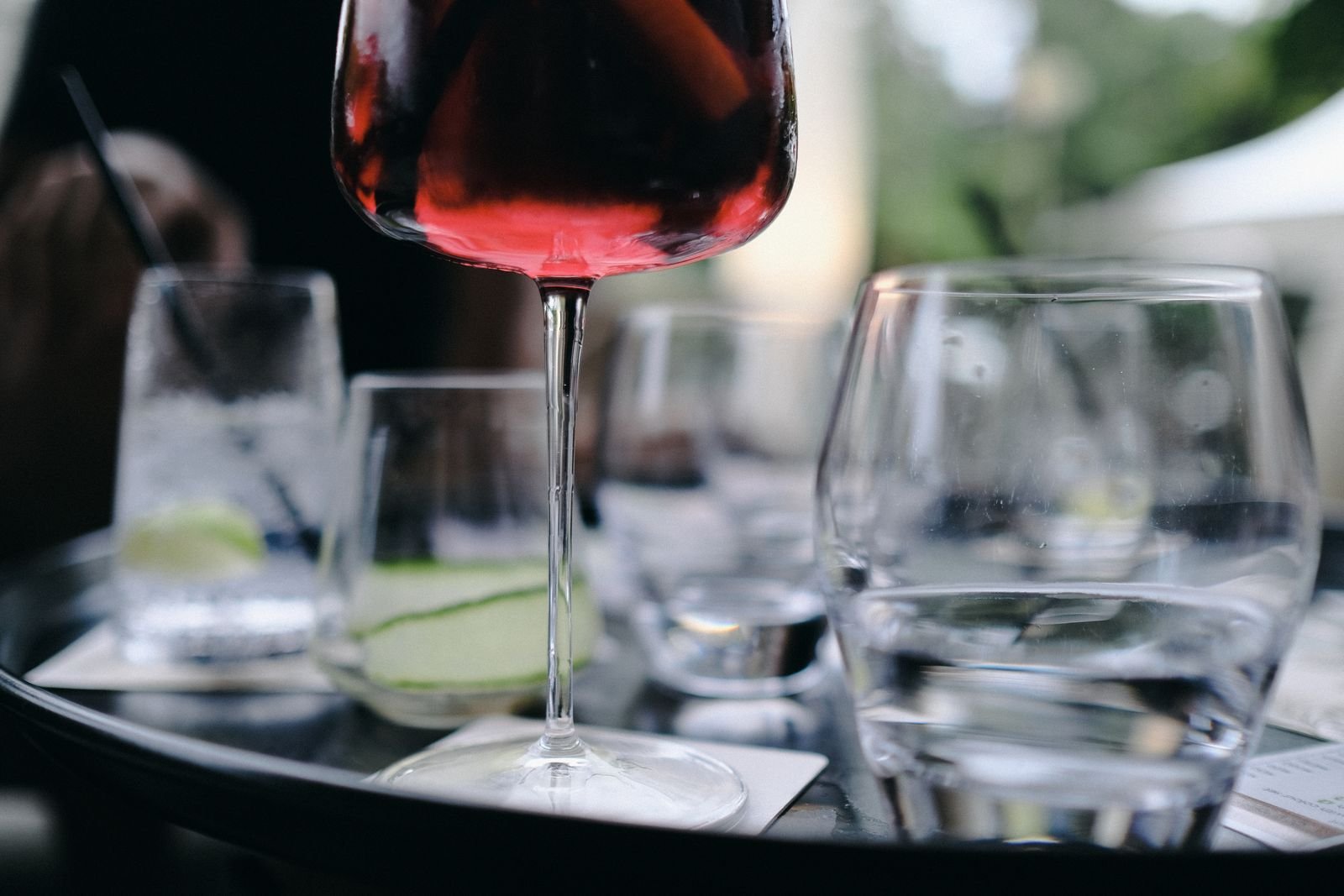 Taça de vinho tinto em primeiro plano sobre mesa de bar, com outras taças desfocadas