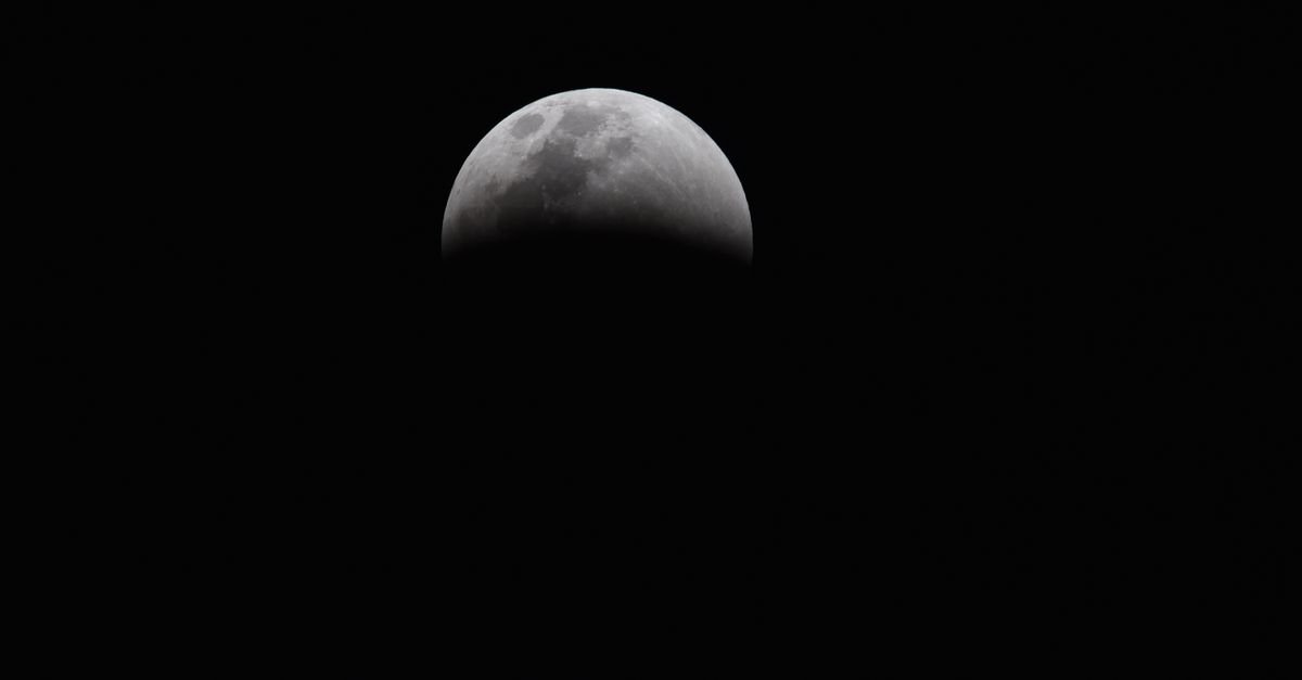 Lua durante eclipse lunar parcial, com a sombra da Terra cobrindo a parte inferior do disco lunar em céu escuro