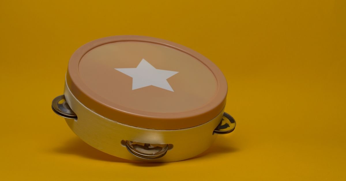 Tamborim, instrumento de percussão usado no samba, sobre fundo amarelo