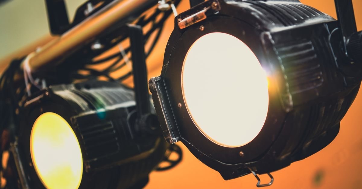 Dois refletores de teatro acesos em close, com luz quente