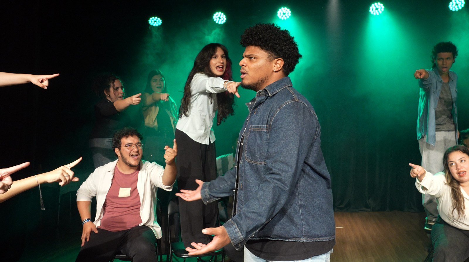 Elenco do musical Entre Sonhos e Sonhos em cena sob luz verde de palco