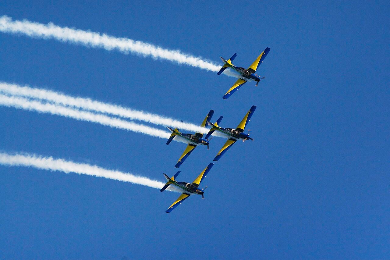 Aviões da Esquadrilha da Fumaça em voo de formação com rastros de fumaça branca