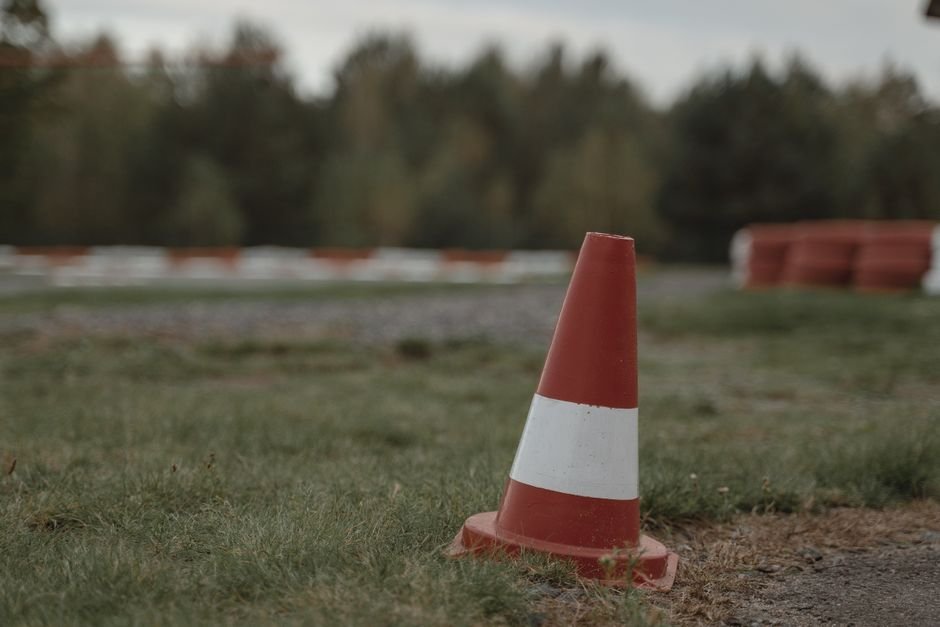 Cone de sinalização laranja e branco posicionado à beira de uma via