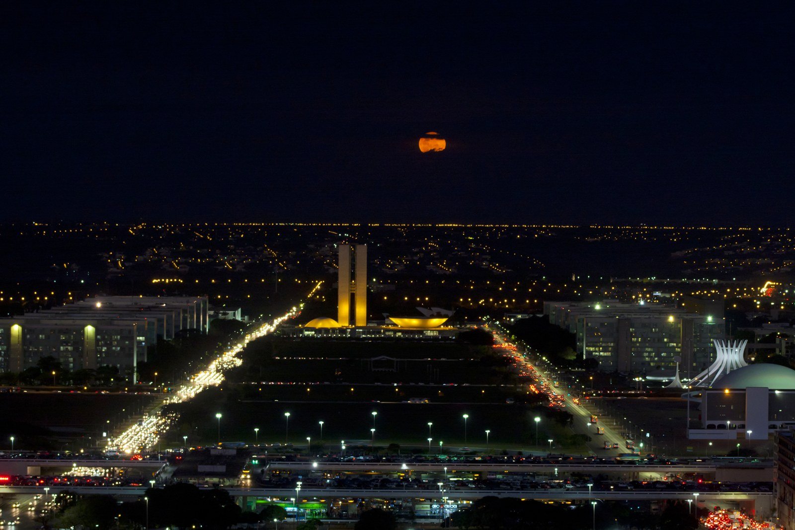 Esplanada dos Ministérios e Congresso Nacional vistos de cima, à noite, com o Eixo Monumental iluminado