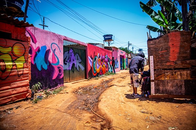 Muros grafitados ao longo de rua de terra no bairro Santa Luzia, na Cidade Estrutural