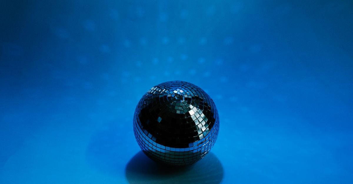 Globo de espelhos refletindo luz sobre fundo azul, em ambiente de festa