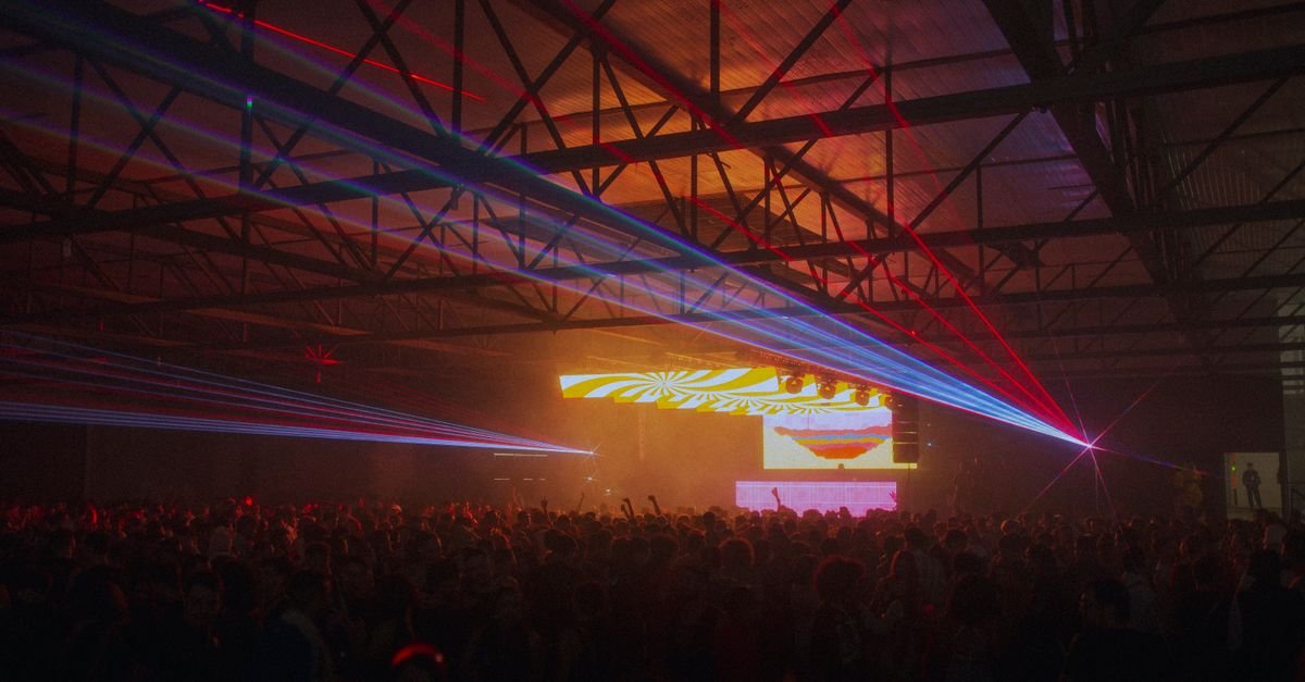 Público em pista de show iluminada por feixes de laser coloridos