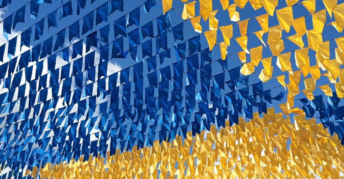 Bandeirinhas de festa nas cores azul e amarela penduradas em fileiras contra o céu