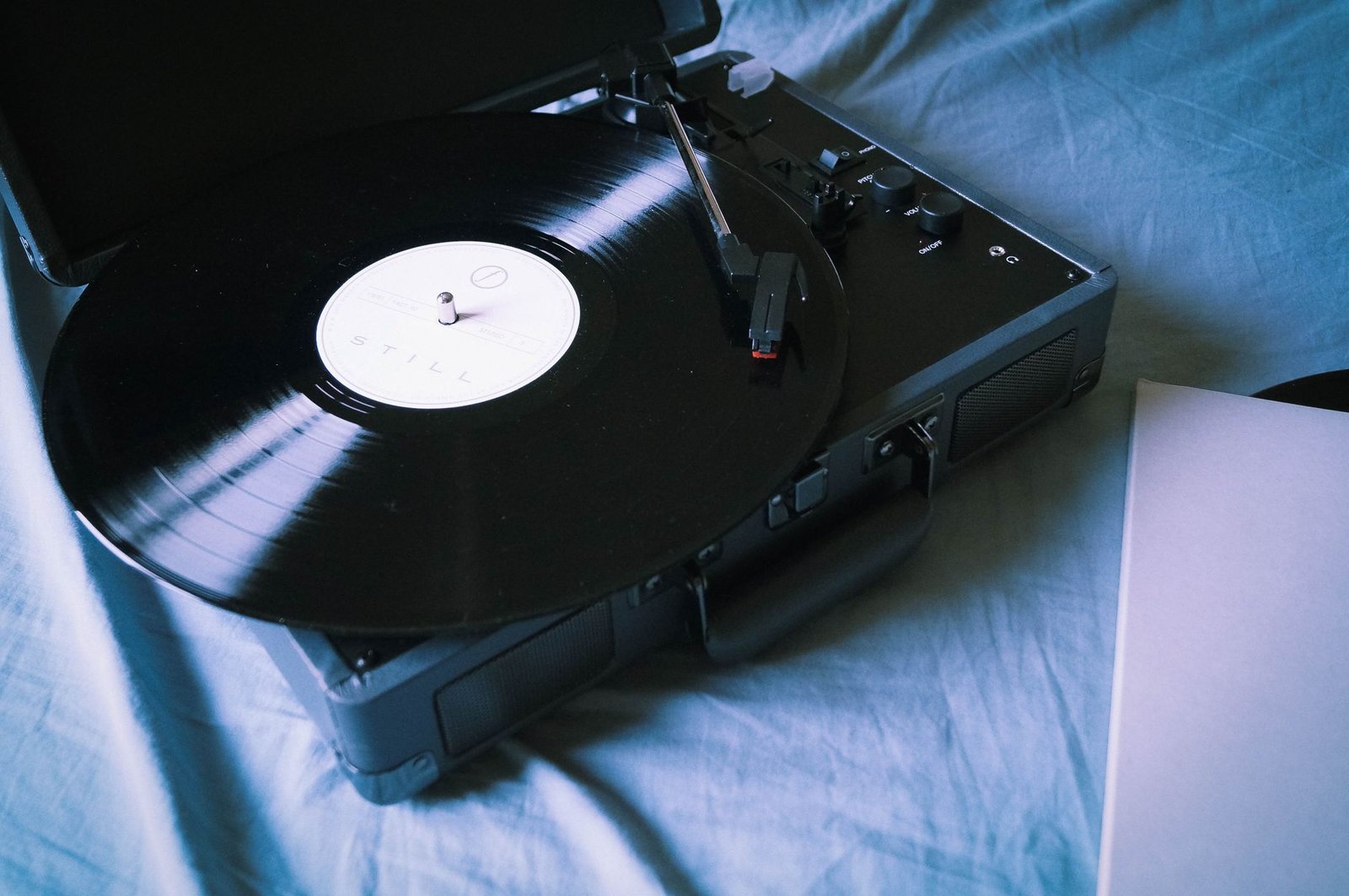 Toca-discos portátil com disco de vinil em cima de uma cama