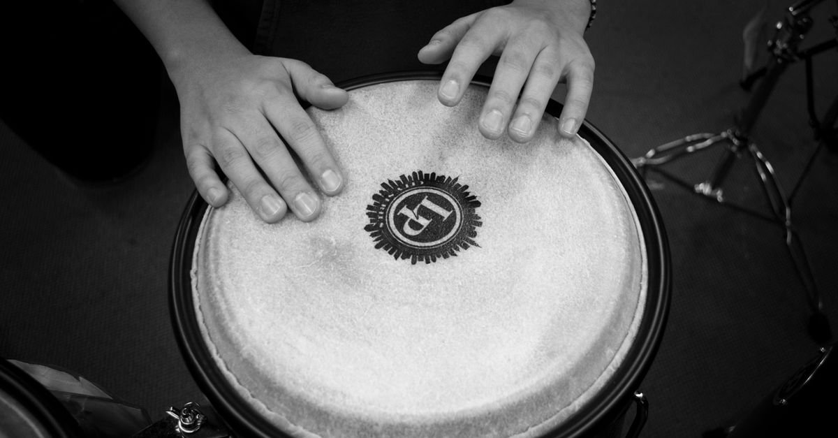 Mãos tocando um instrumento de percussão de couro