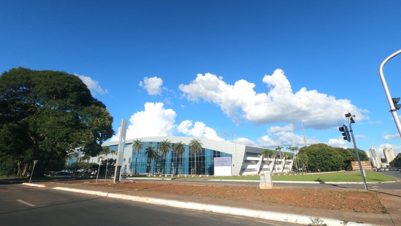 Ulysses Centro de Convenções visto do gramado em frente, com palmeiras e céu azul