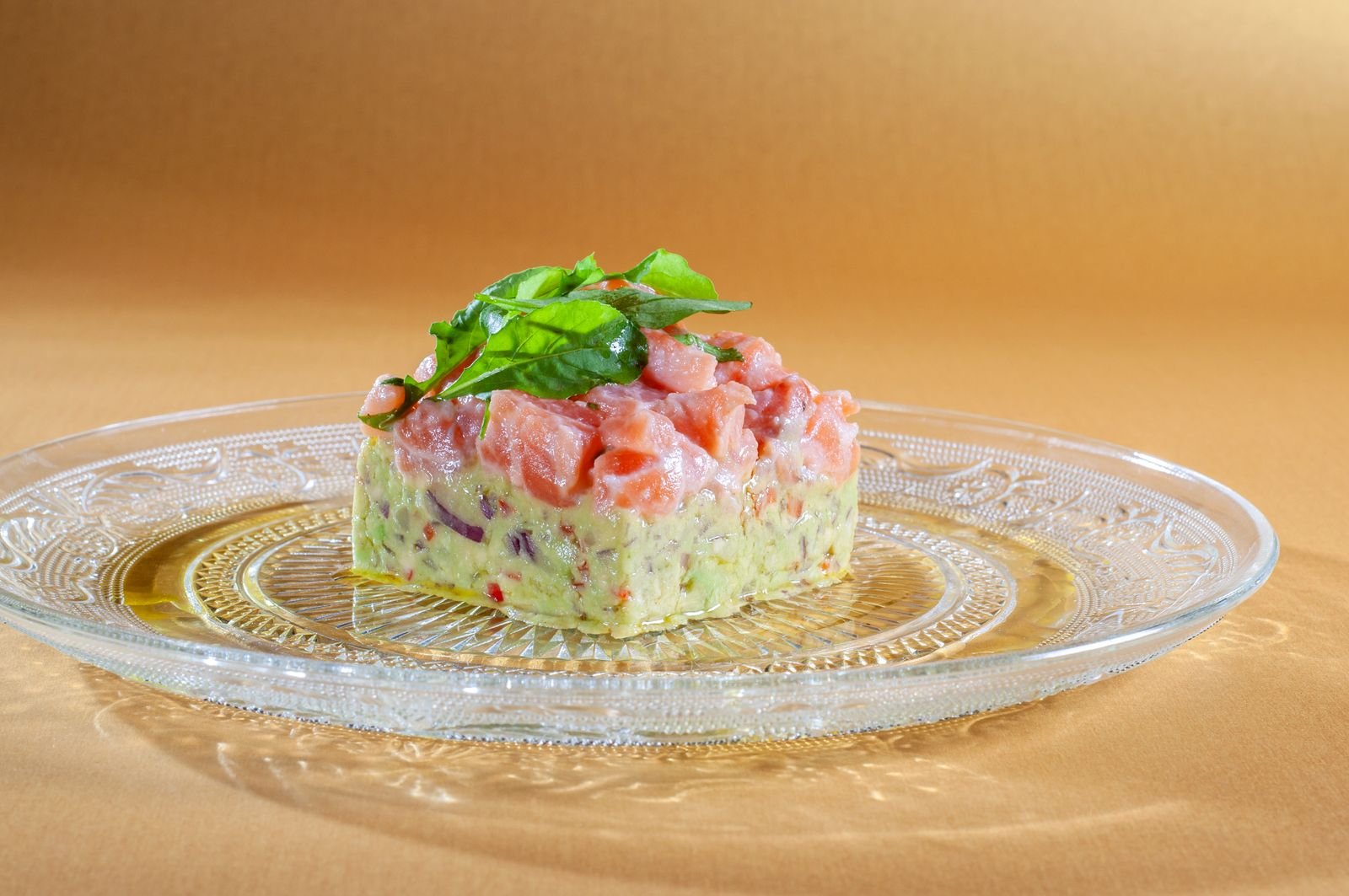 Tartare de salmão sobre base de abacate em prato de vidro (foto ilustrativa de banco, não é do Gurumê)