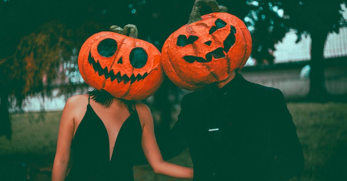 Casal com máscaras de abóbora iluminadas em festa de Halloween
