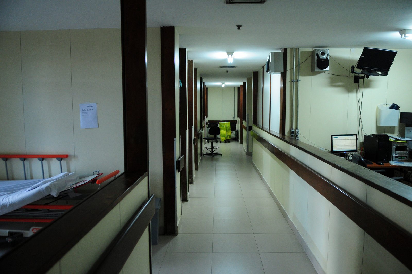 Corredor de enfermaria do Hospital de Base do DF, com leito à esquerda e posto de enfermagem à direita