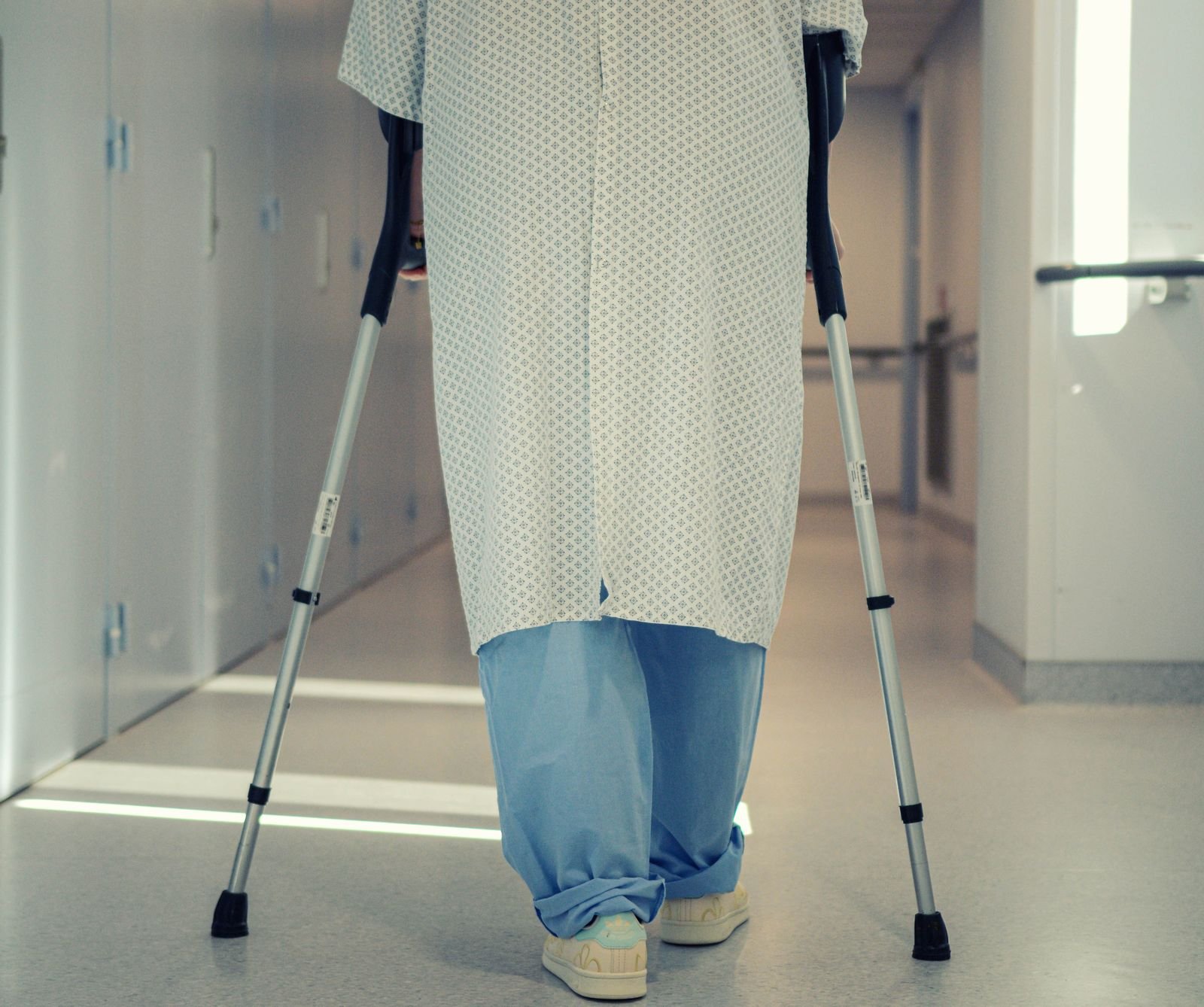 Paciente usa muletas para caminhar em corredor de hospital