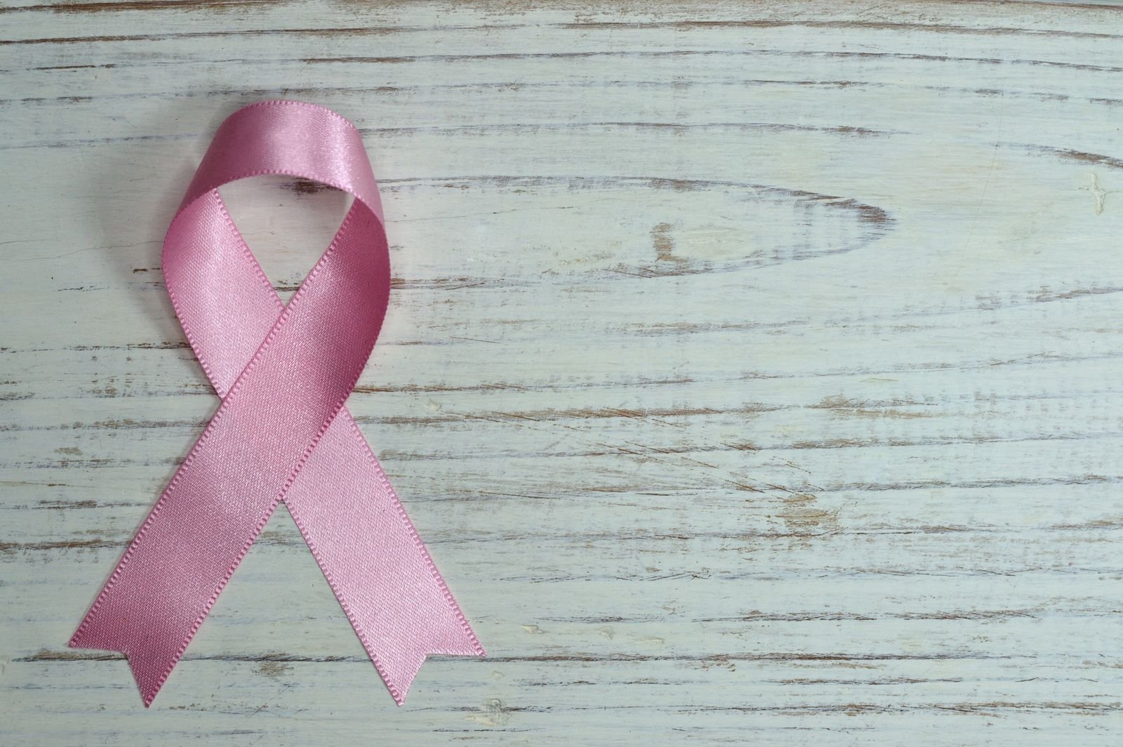 Laço rosa de cetim sobre madeira clara, símbolo da campanha Outubro Rosa (foto ilustrativa)