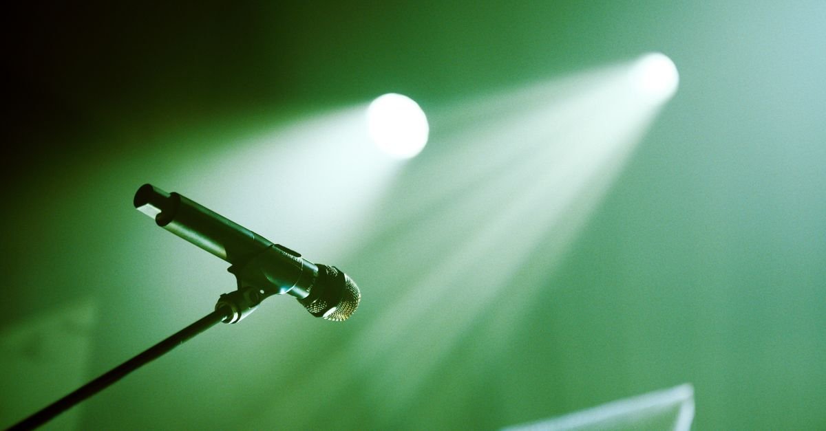 Microfone em pedestal iluminado por luz verde de palco