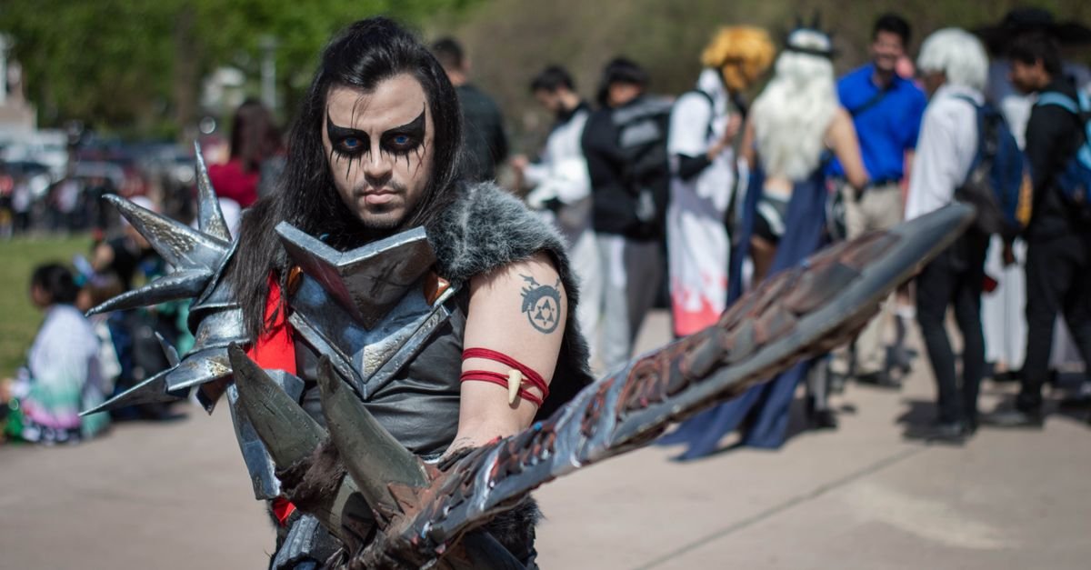 Participante fantasiado com armadura e espada em encontro de cosplay ao ar livre
