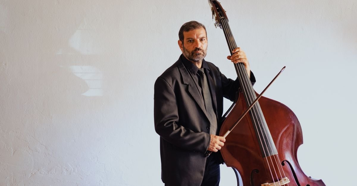 Contrabaixista de terno tocando contrabaixo acústico com arco