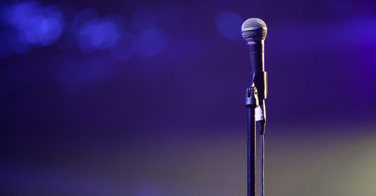 Microfone em pedestal iluminado por luz roxa de palco