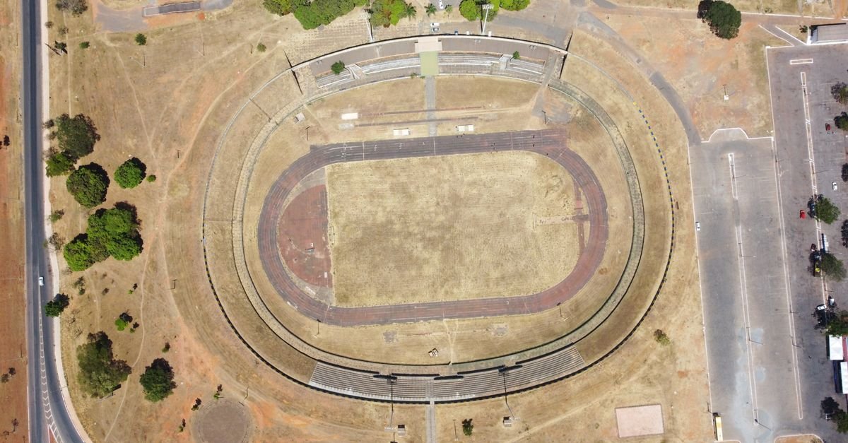 Vista aérea de estádio com pista de atletismo em Brasília cercado por área verde do cerrado