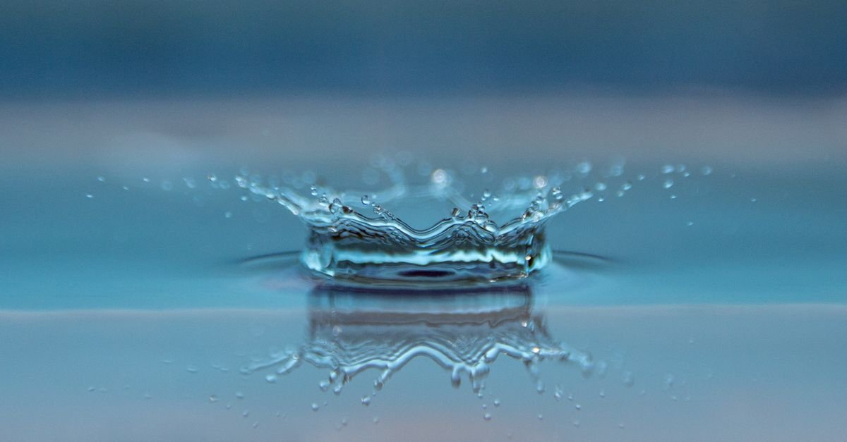 Gota de água caindo sobre uma superfície líquida e formando coroa e ondas concêntricas