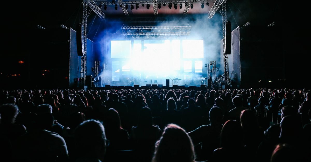 Público diante de palco iluminado em show ao ar livre