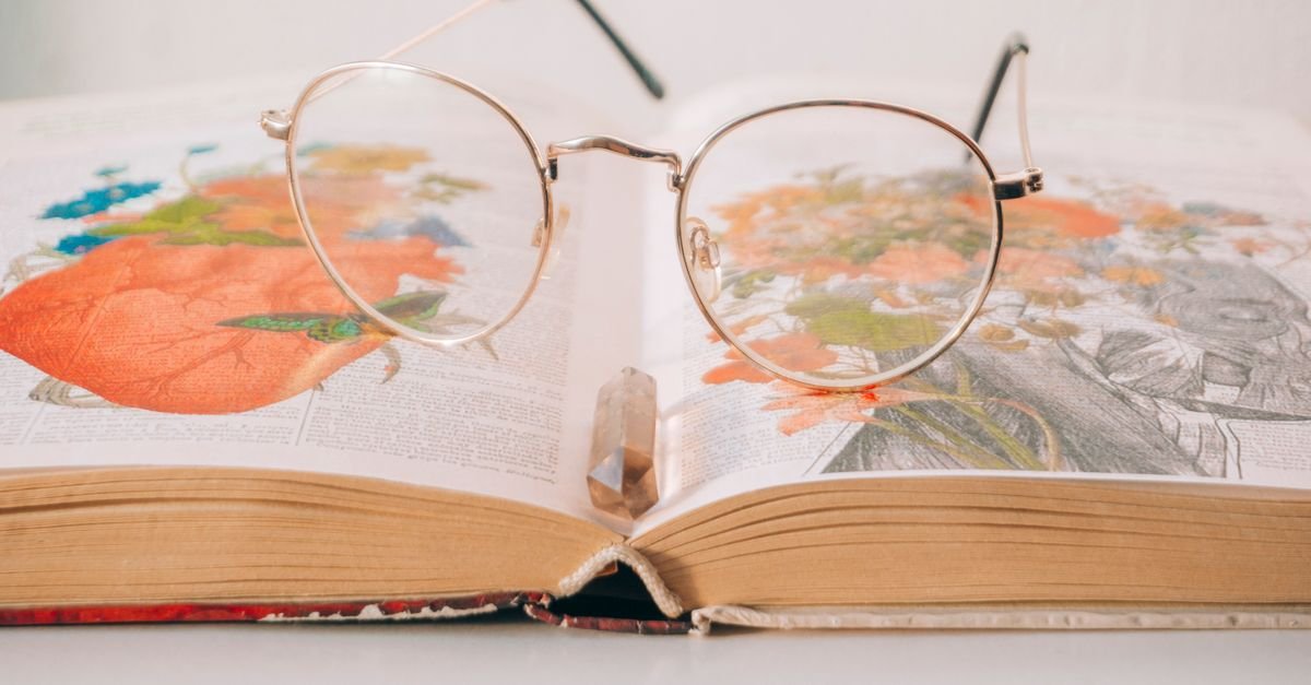 Oculos apoiado sobre livro aberto com paginas ilustradas