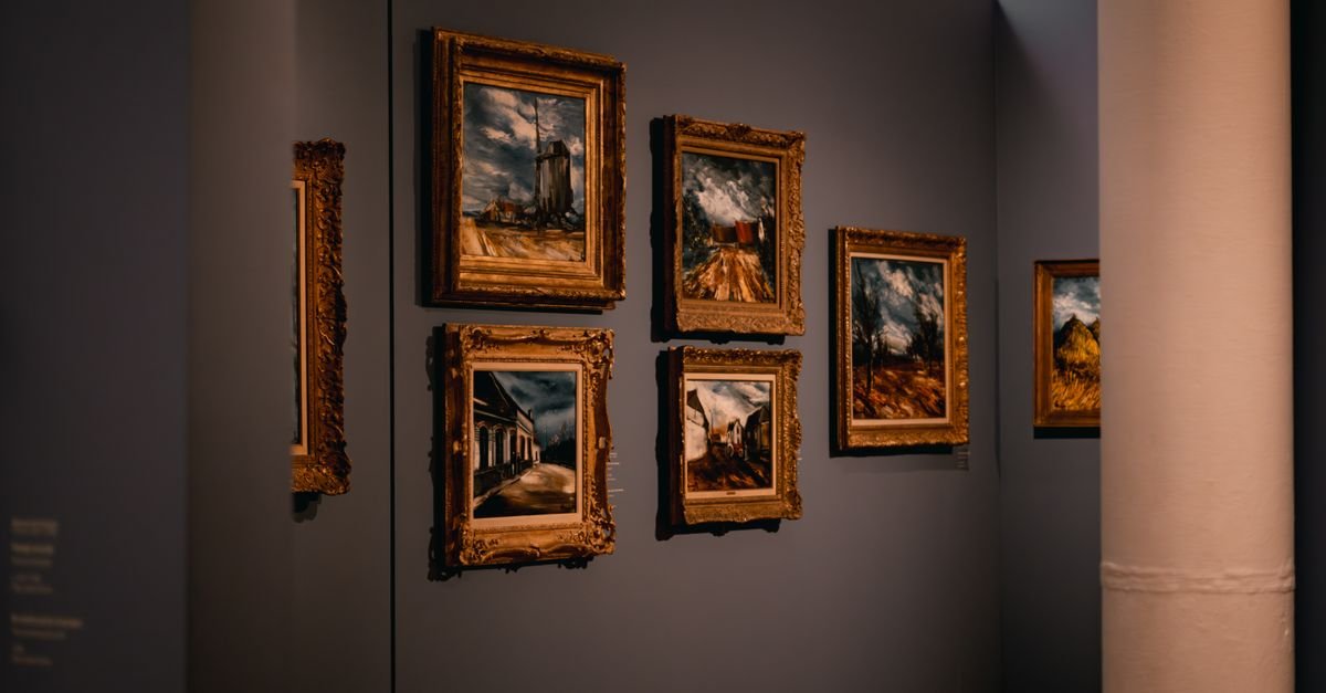 Parede de galeria de museu com quadros emoldurados sob iluminação baixa