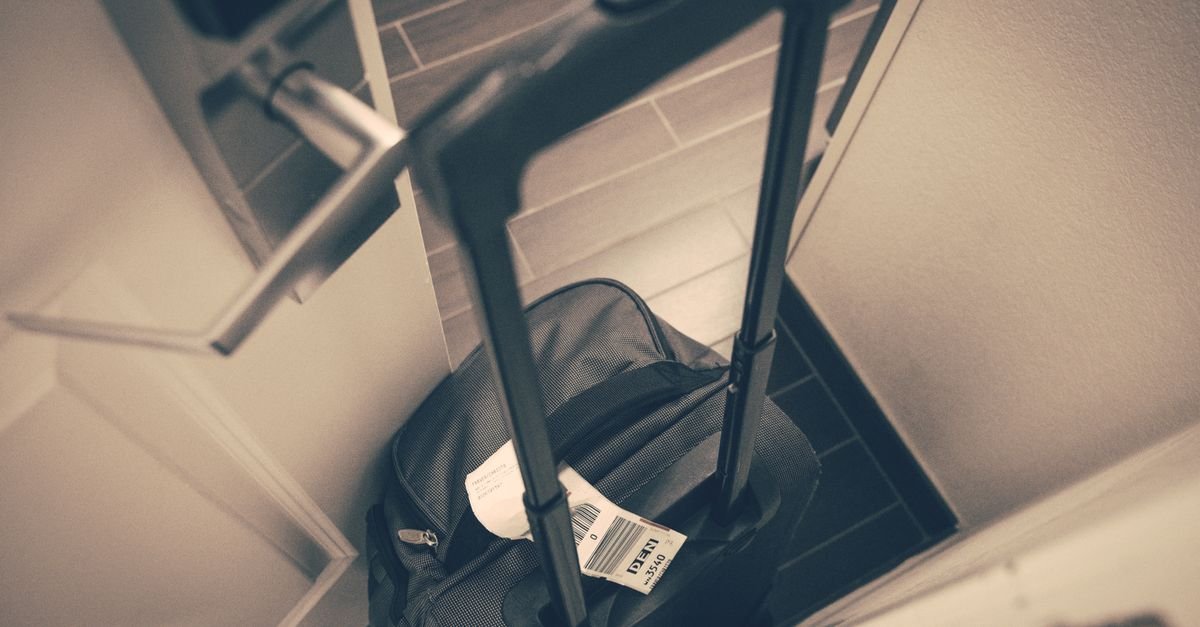 Mala de viagem com etiqueta de bagagem parada junto à porta de um quarto de hotel