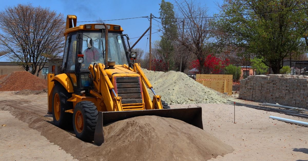 Máquina pesada amarela com pá carregadeira em operação sobre terreno de terra, imagem ilustrativa