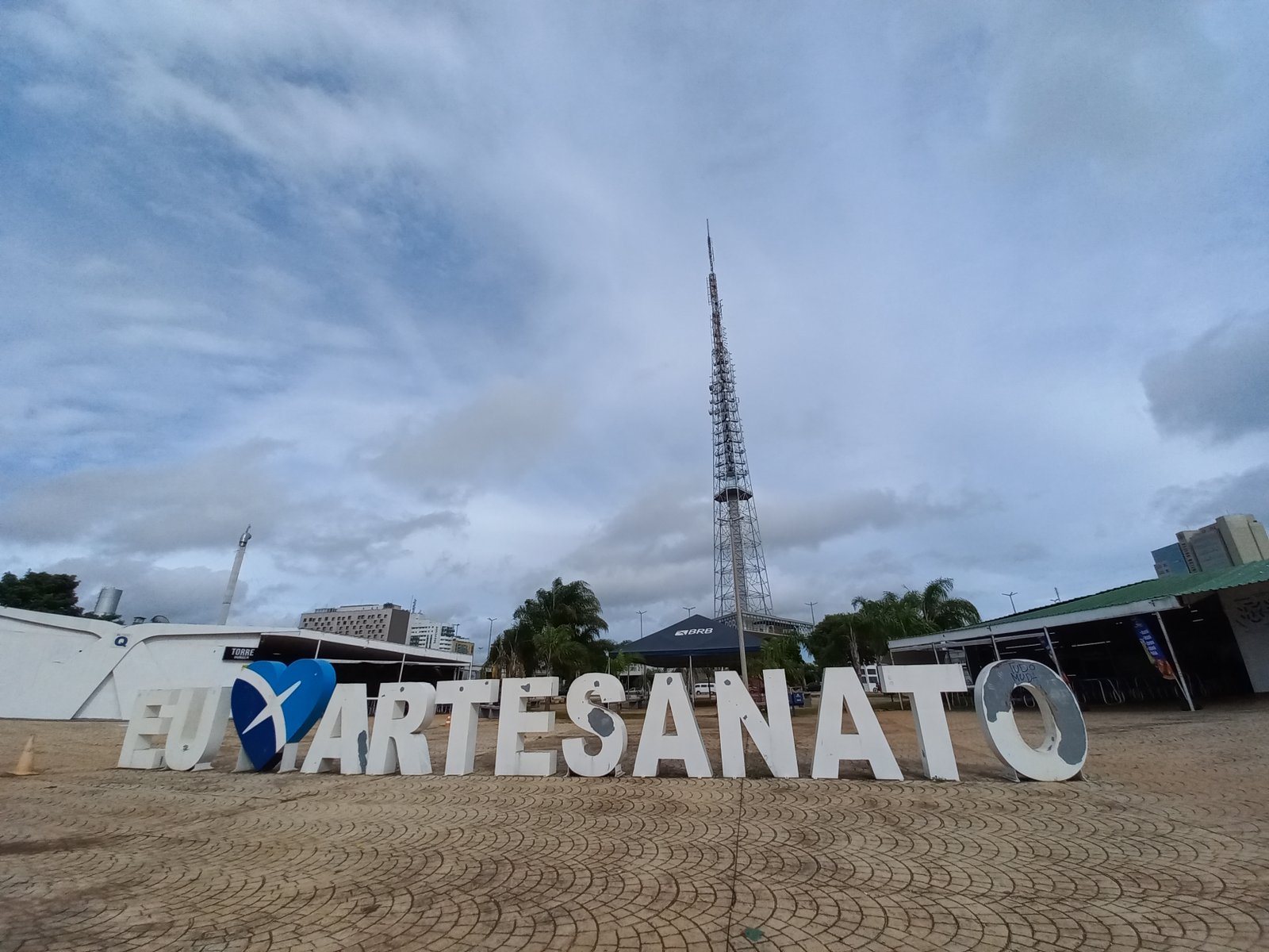 Letreiro Eu Amo Artesanato na base da Torre de TV de Brasília, com a torre ao fundo sob céu nublado