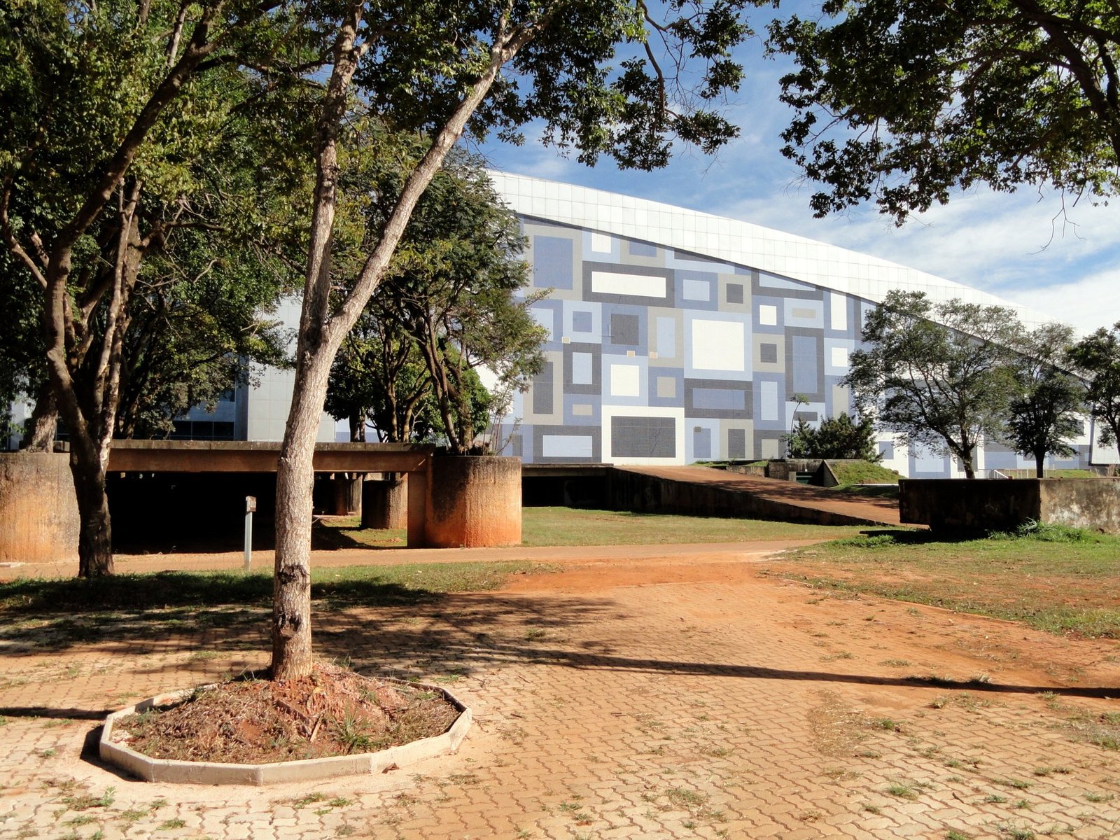 Fachada curva do Centro de Convenções Ulysses Guimarães, em Brasília, vista entre árvores