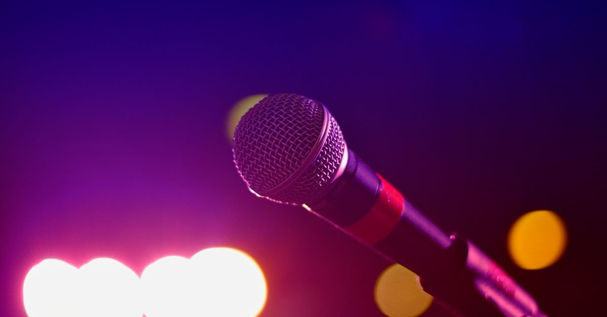 Microfone em primeiro plano diante de luzes coloridas de palco