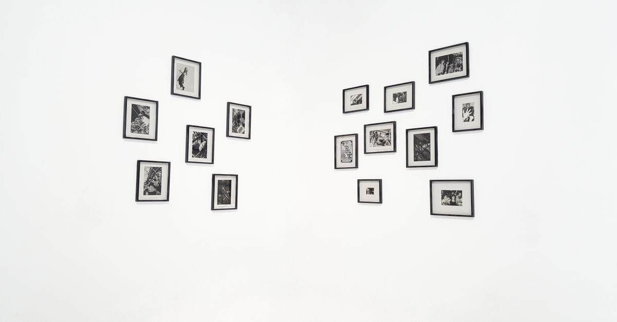 Parede branca de galeria com fotografias em preto e branco emolduradas