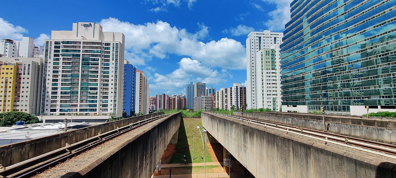 Trilhos elevados do Metrô-DF cortando Águas Claras entre prédios residenciais em dia de céu azul