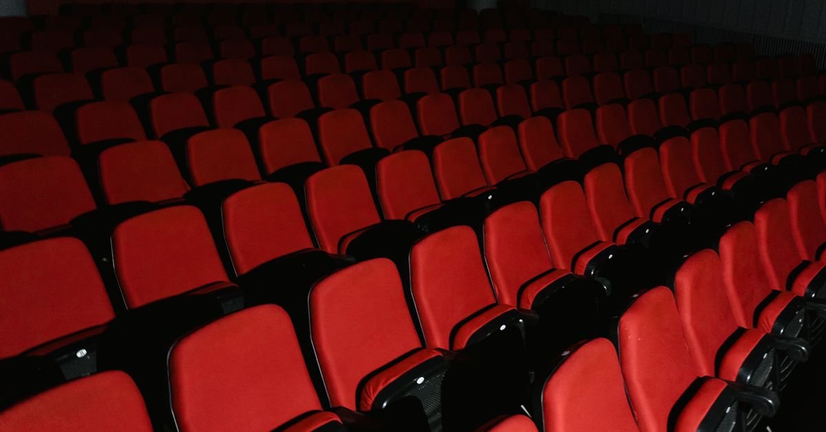 Fileiras de poltronas vermelhas vazias em sala de cinema