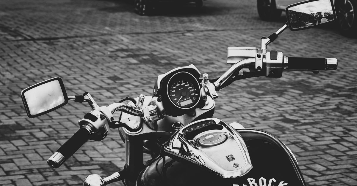 Painel e guidão de motocicleta estacionada em rua de paralelepípedo