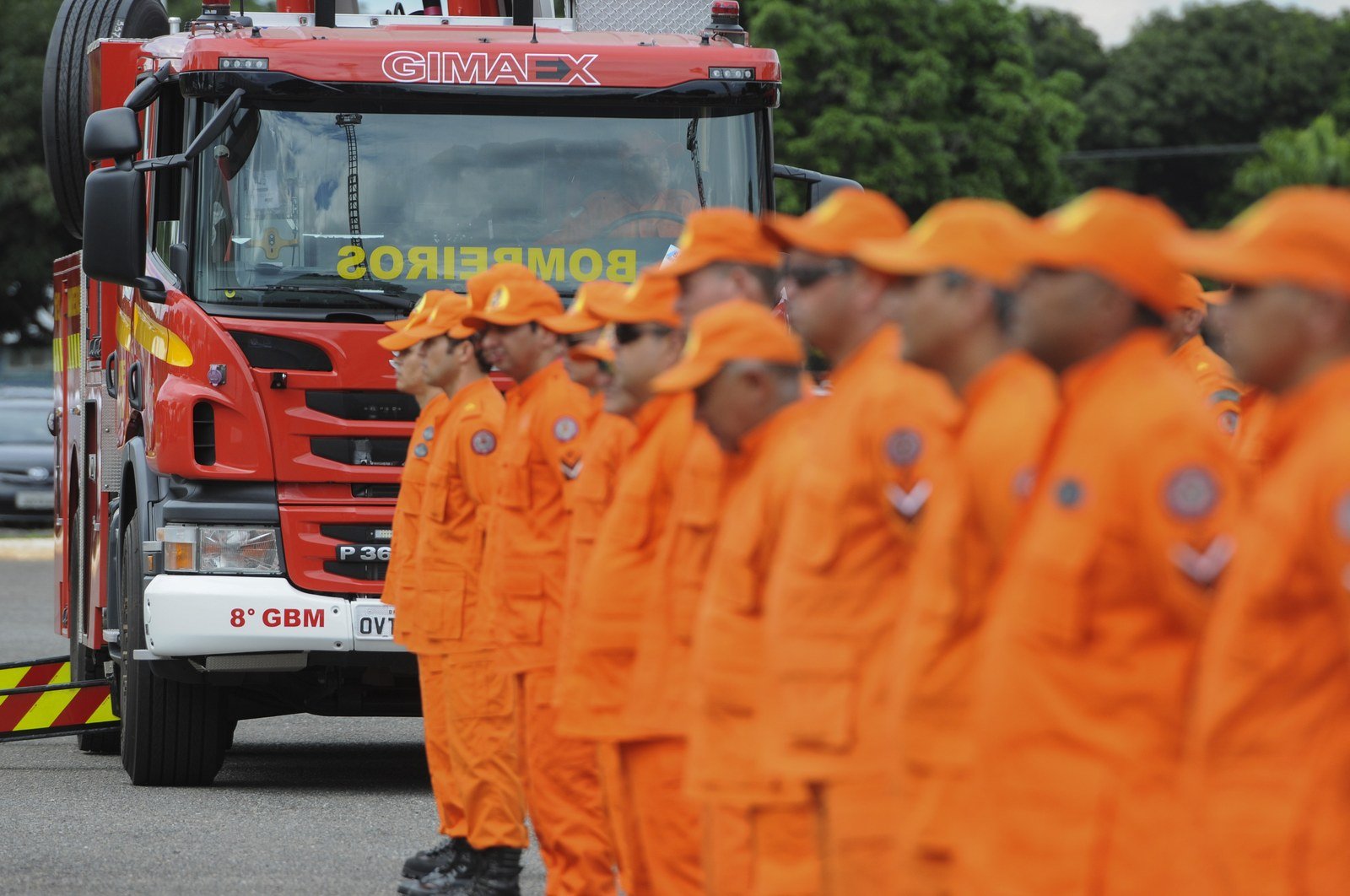 Bombeiros perfilados ao lado de caminhão de combate a incêndio do 8º GBM
