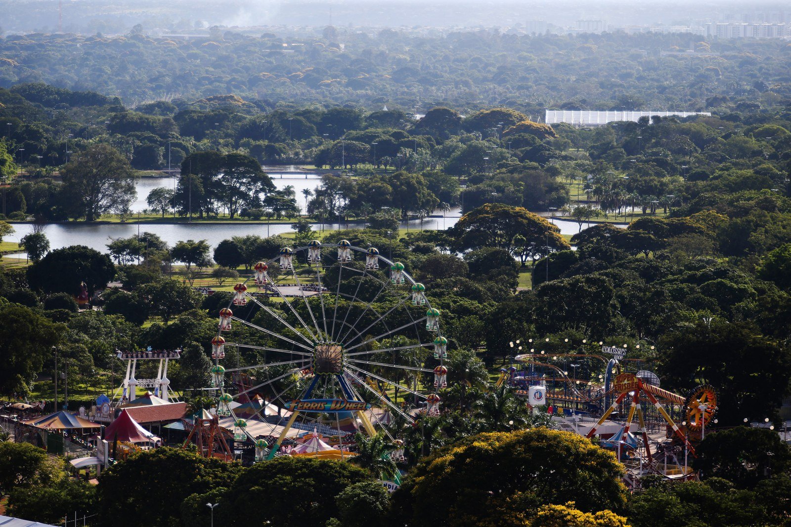 Vista aérea da roda-gigante e dos brinquedos do Nicolândia, cercados de árvores no Parque da Cidade, em Brasília.