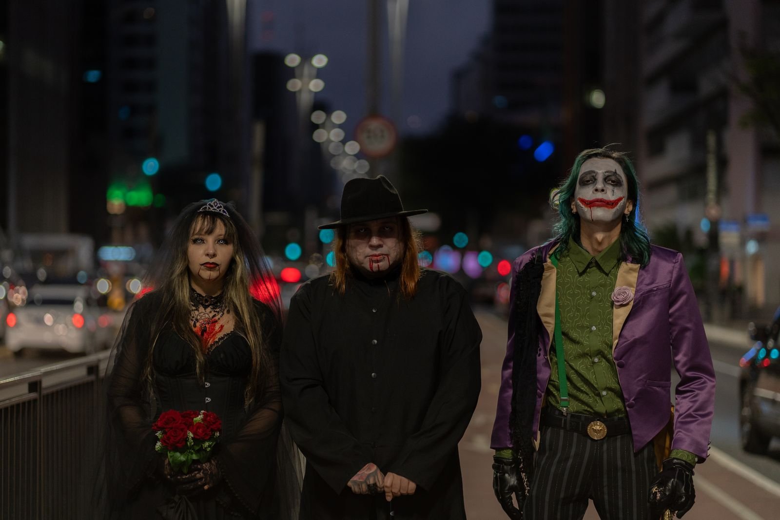 Três pessoas com fantasias de Halloween em rua à noite