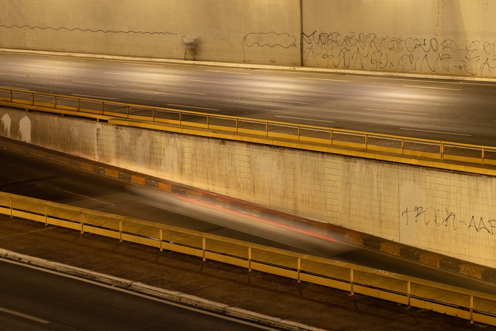 Longa exposição de um túnel urbano em Brasília à noite, com rastro de luz de um carro