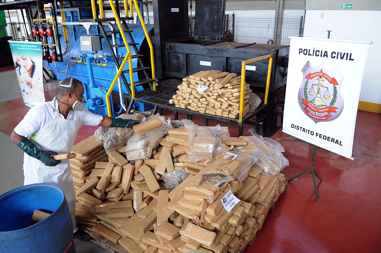 Tabletes de droga apreendidos empilhados ao lado de banner da Polícia Civil do Distrito Federal