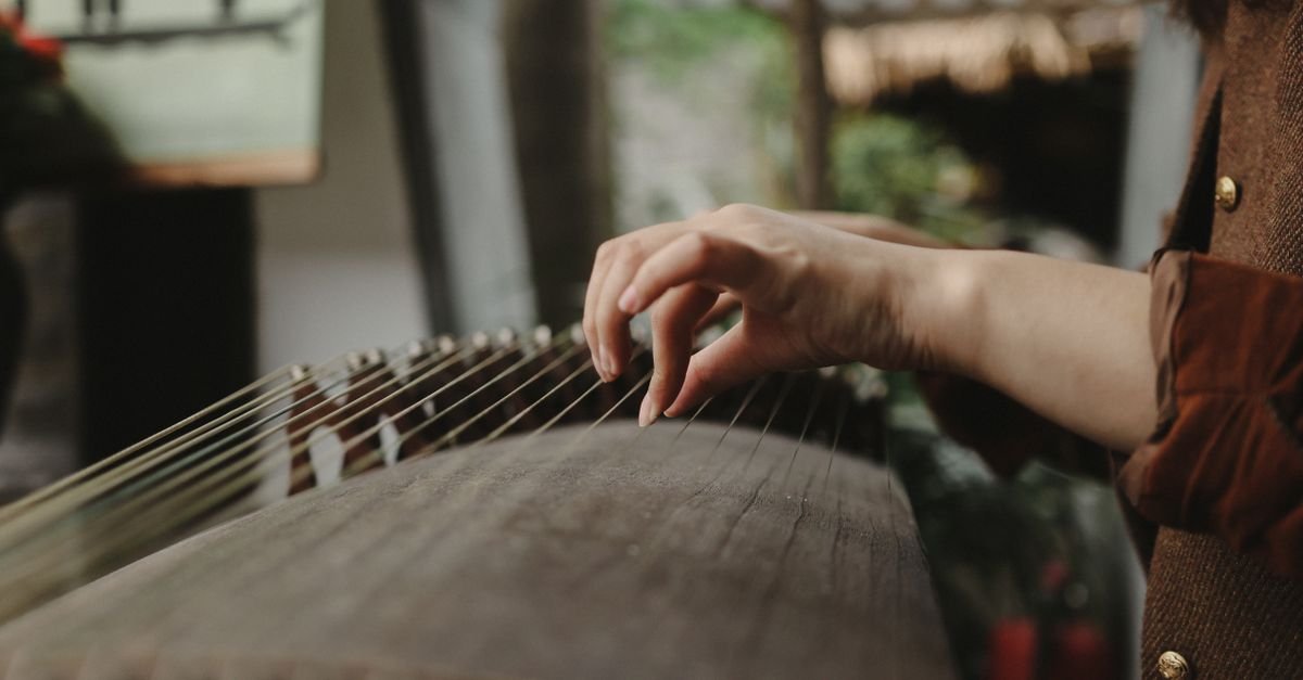 Mãos tocando as cordas de um instrumento tradicional chinês de mesa
