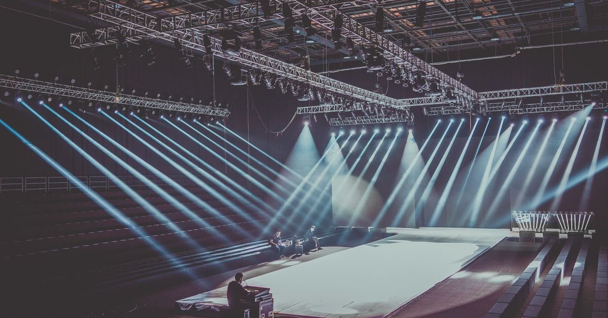 Palco de teatro vazio com feixes de luz azul apontados para a área de cena