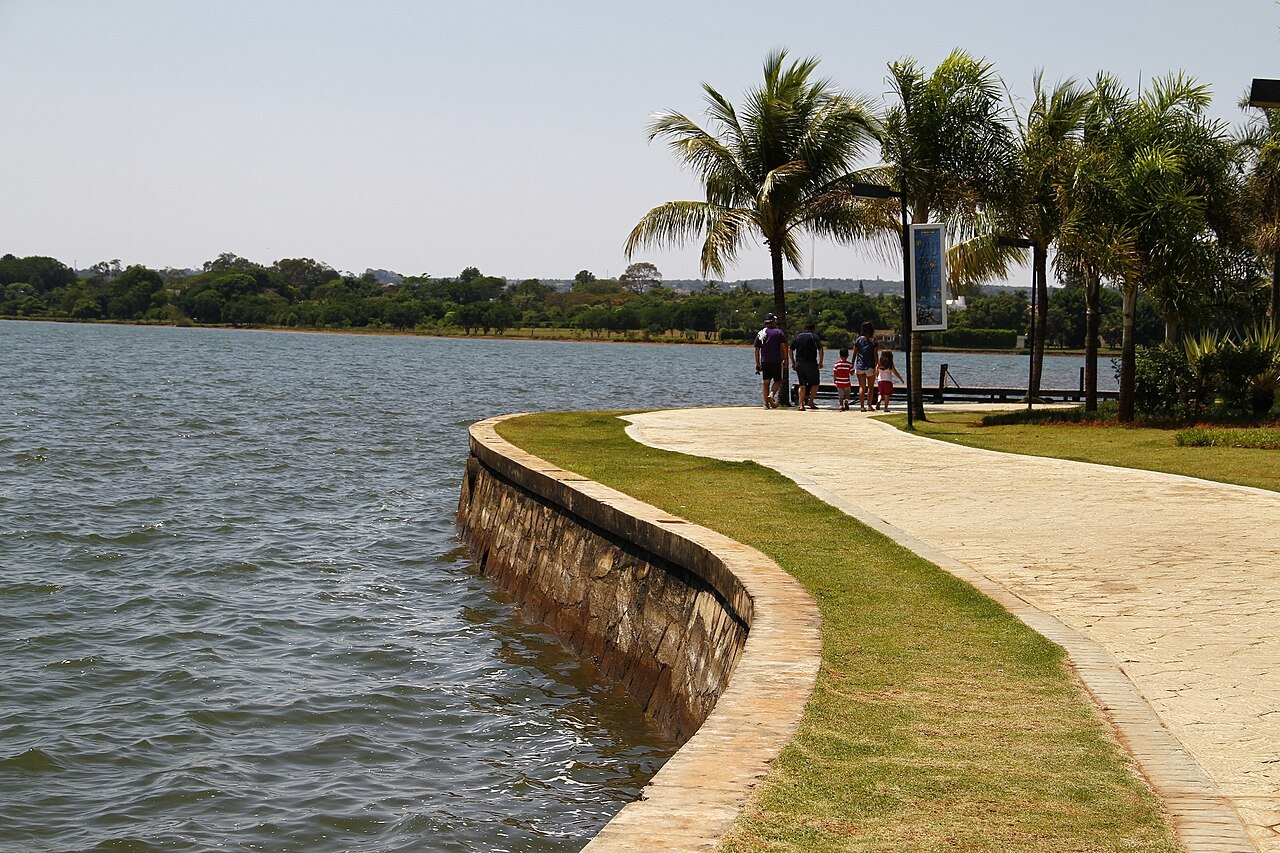 Calçadão do Pontão do Lago Sul à beira do Lago Paranoá, com palmeiras e píer ao fundo