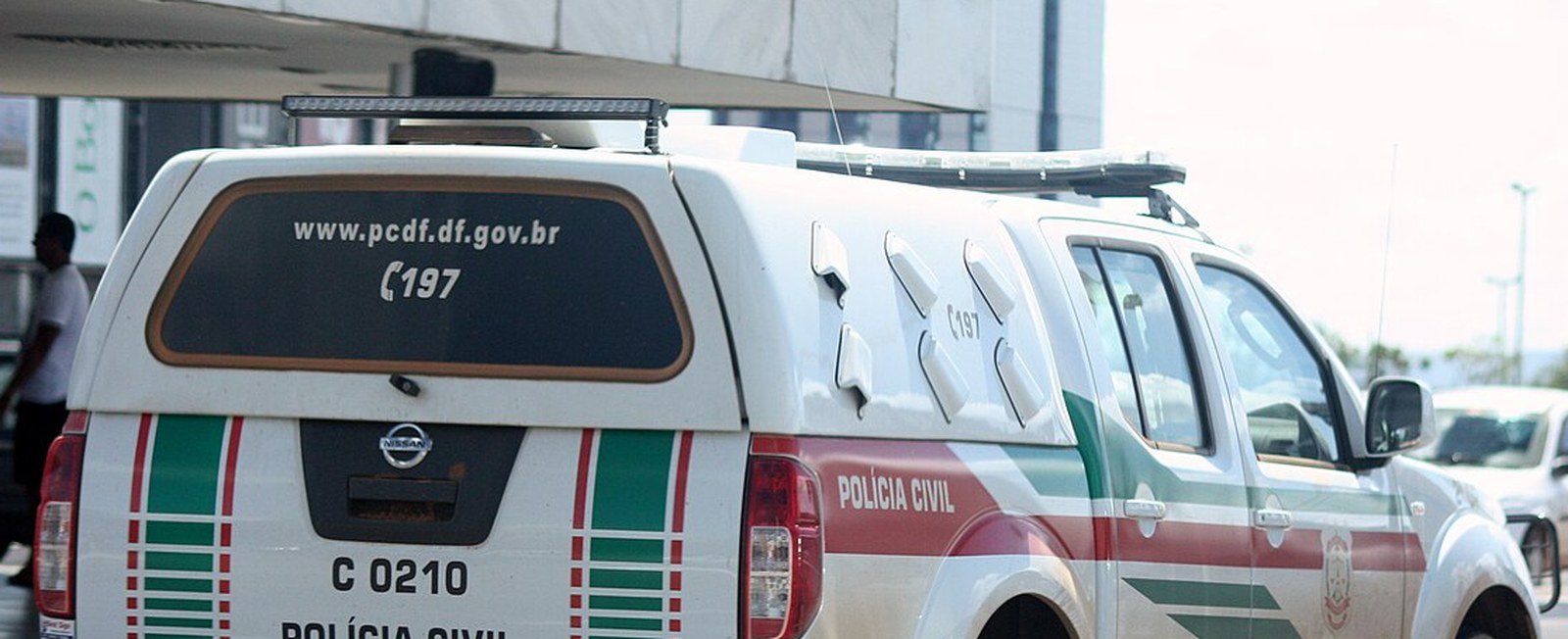Viatura da Polícia Civil do Distrito Federal, branca com faixas verdes e vermelhas, parada em via da cidade