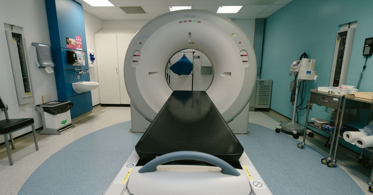 Sala de exame de imagem com tomografo e maca posicionada para o equipamento