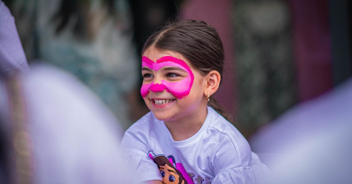 Criança sorri com o rosto pintado durante festival infantil