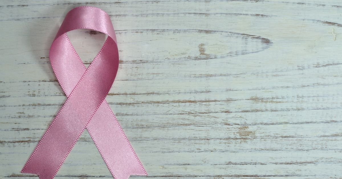 Laço rosa sobre superfície de madeira clara, símbolo da campanha de prevenção ao câncer de mama